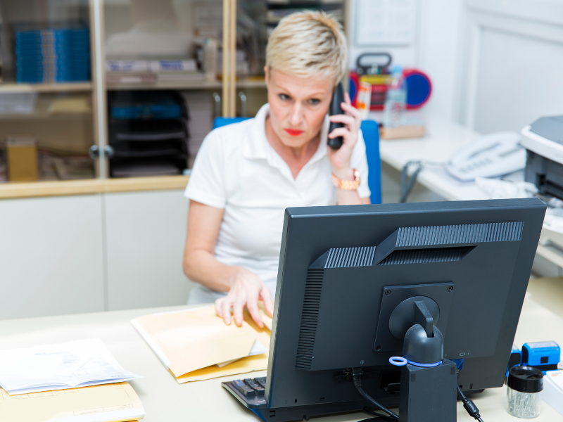 woman sits at desk on the phone